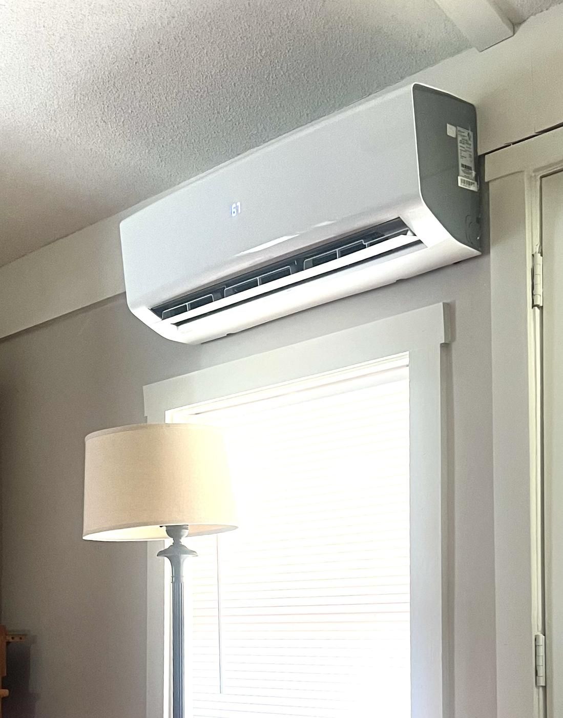 Ductless mini split unit mounted on a wall above a window